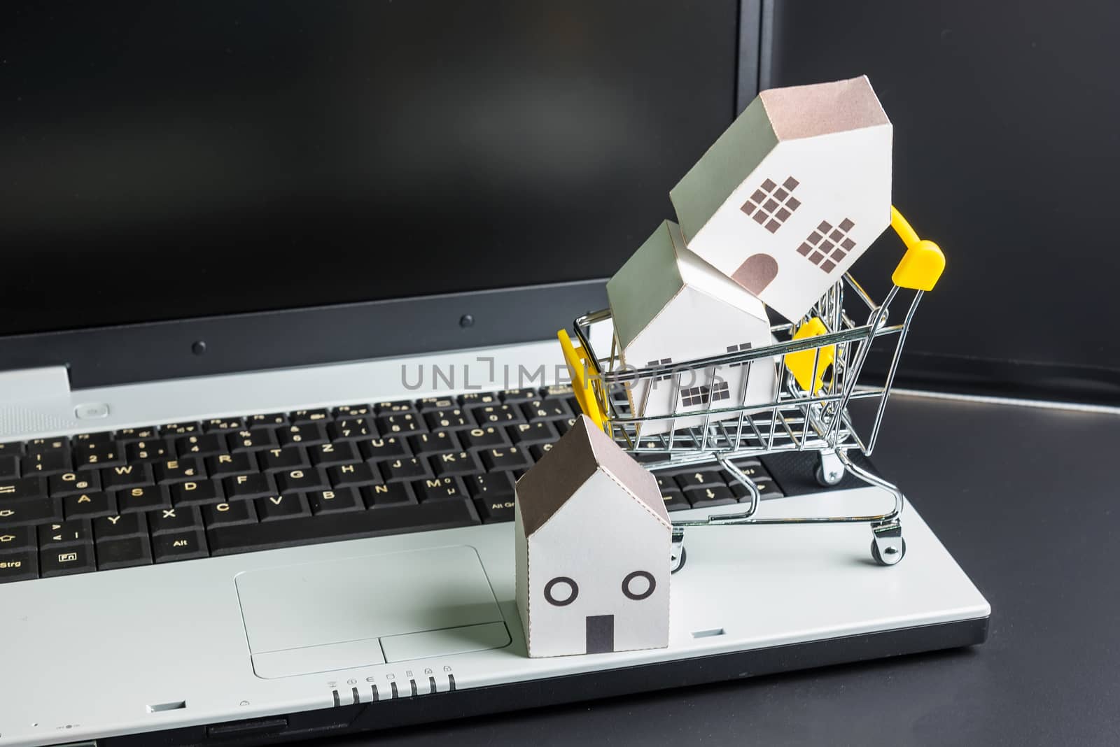 Shopping cart full of paper hose model on laptop notebook.Online shopping concept.Real estate concept, New house concept.Buying a house.
