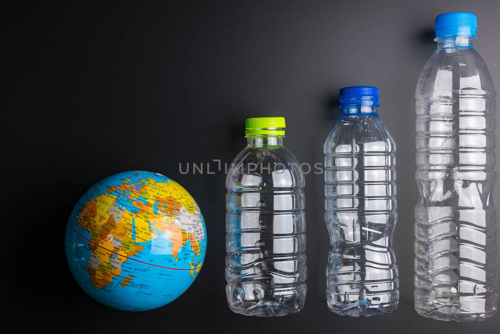 Earth world globe and plastic bottle waste on the black background.Saving the planet Earth from plastic bags concept.Global warming.Plastic waste overflows the world