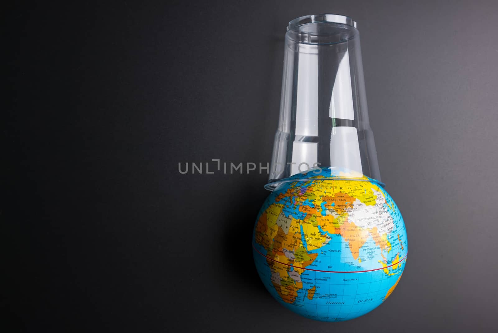 Earth world globe and plastic glass waste on the black background.Saving the planet Earth from plastic bags concept.Global warming.Plastic waste overflows the world