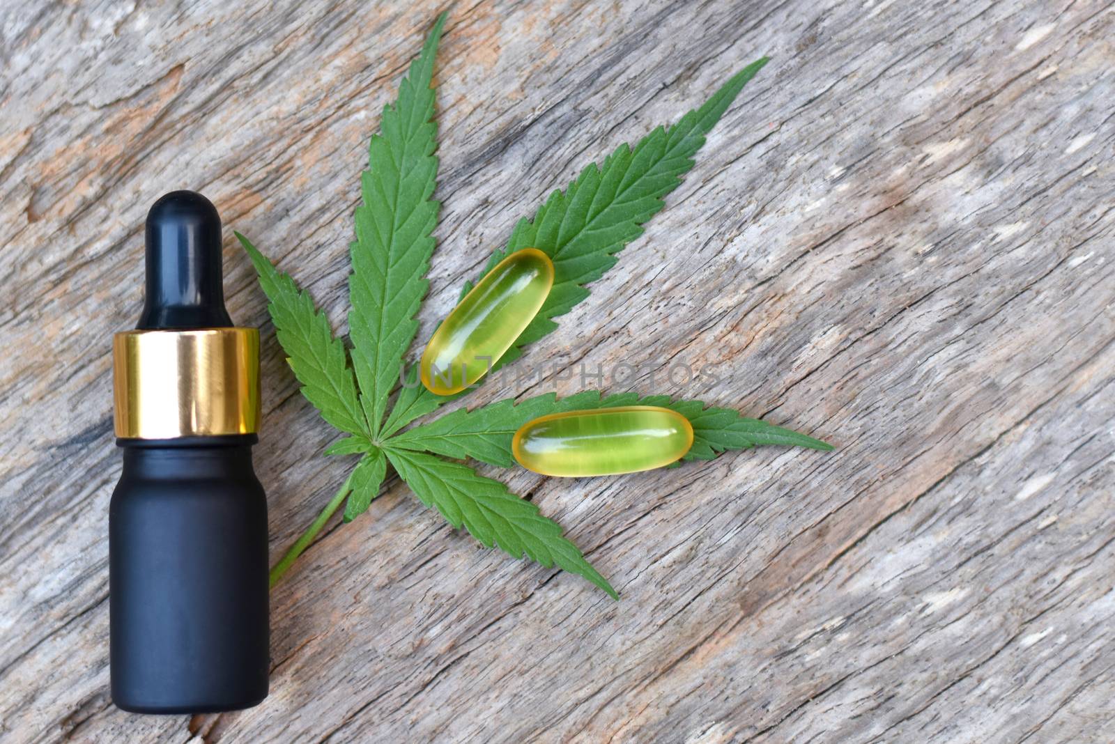 Medical Marijuana, Bottle and Capsule of CBD hemp oil and cannabis leaves on wooden background. Medical concept Researching hemp leaves and hemp oil Using oil as a treatment herb. Selected focus