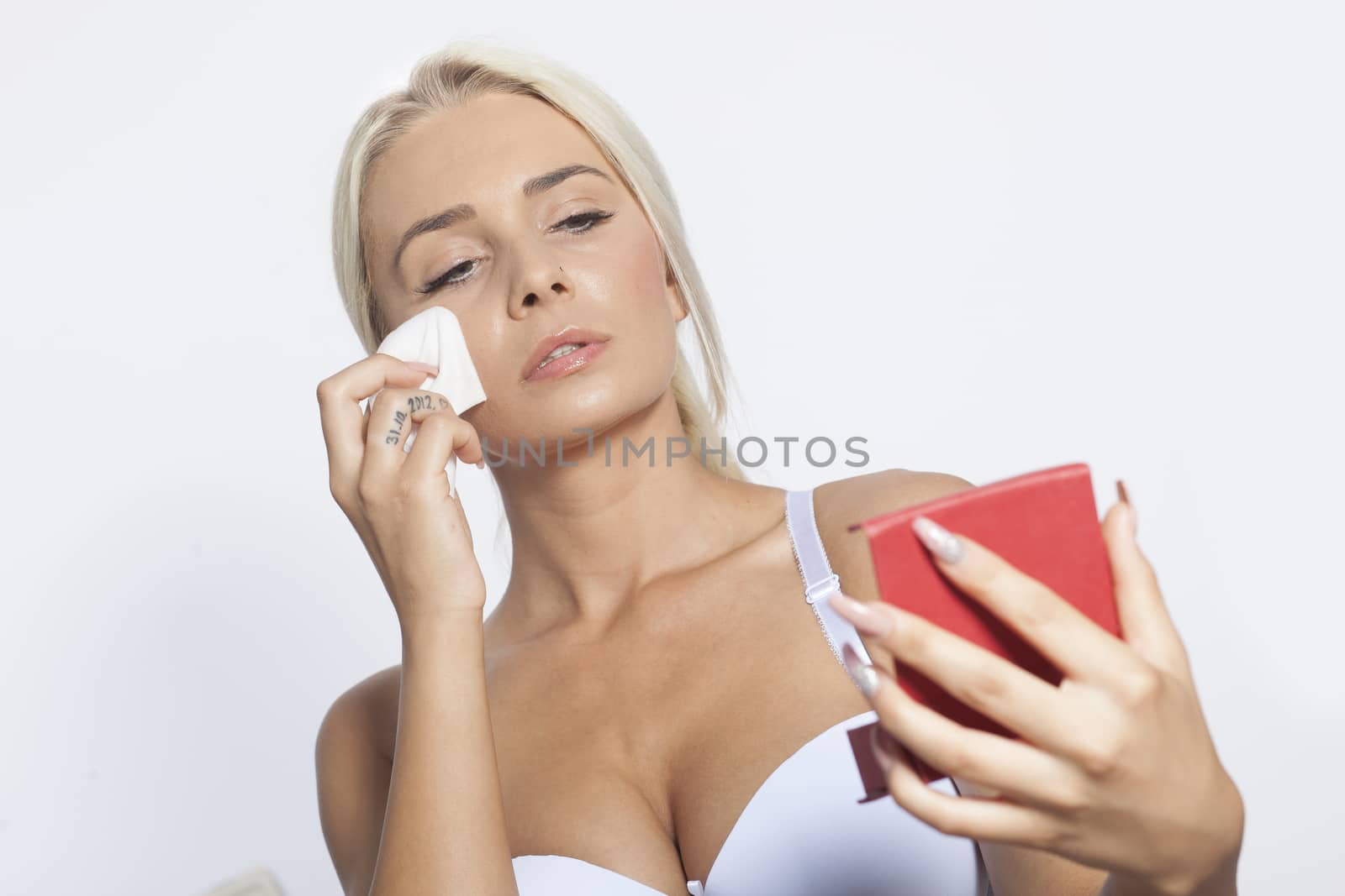 Young woman clean face with wet wipes and holding mirror by adamr