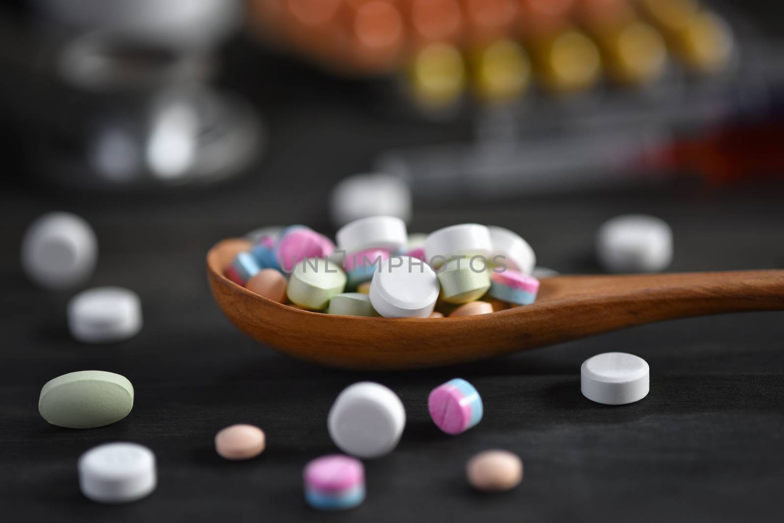 Assorted pharmaceutical medicine pills, tablets and capsules in wooden spoon on a black wooden background. Medicine concepts. Minimalistic abstract concept. Selected focus