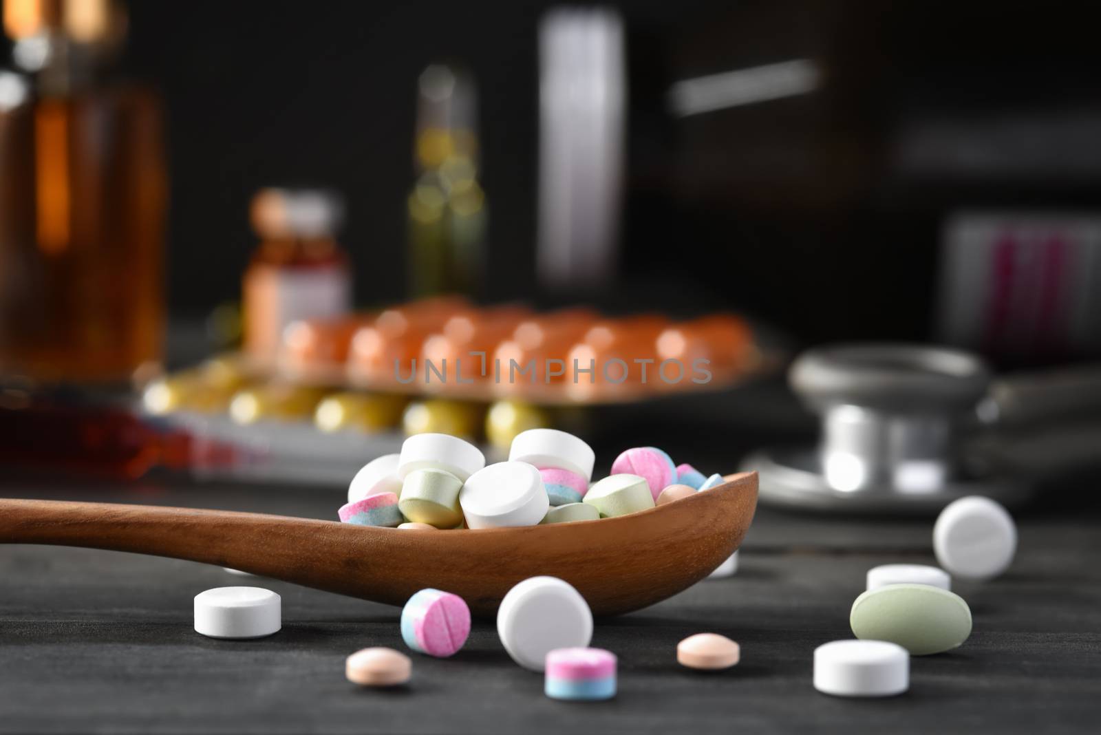 Assorted pharmaceutical medicine pills, tablets and capsules in wooden spoon on a black wooden background. Medicine concepts. Minimalistic abstract concept. Selected focus