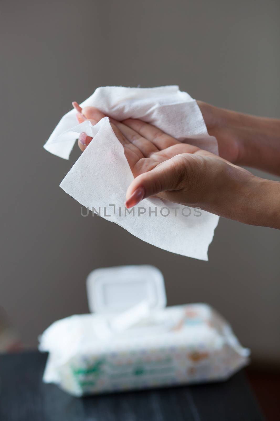 Woman clean hands with wet wipes, blurred package in background