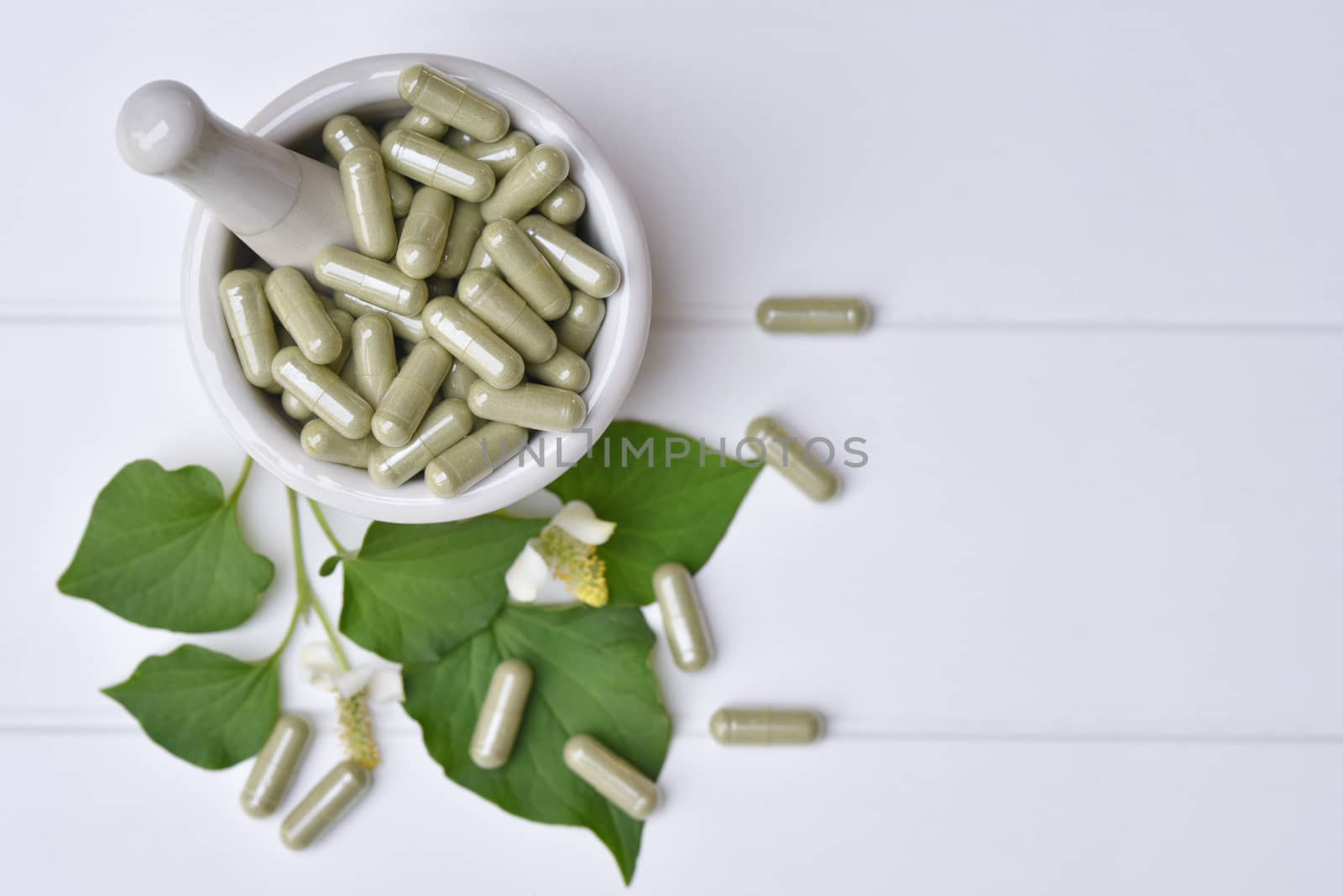 Top view Herbal medicine in capsules from Houttuynia cordata or chameleon fish mint leaf in Mortar medicine on white background. with copy space for medical background. healthy natural product.