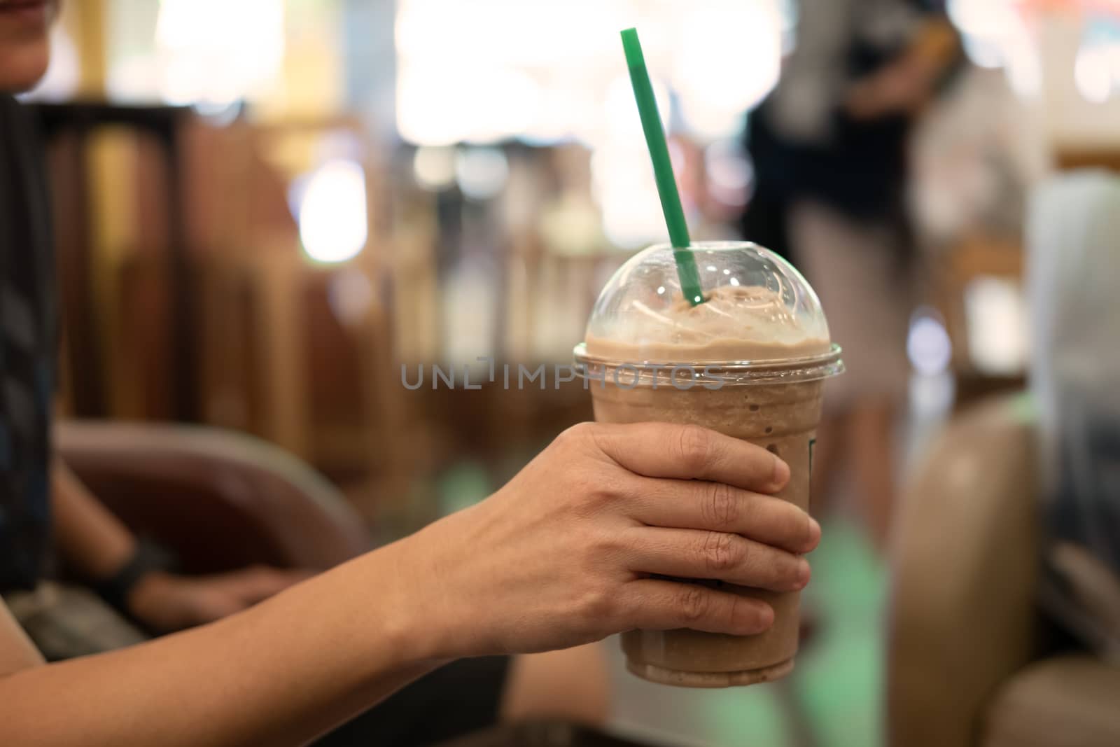 Woman holding plastic glass of iced coffee with milk, image for beverage.