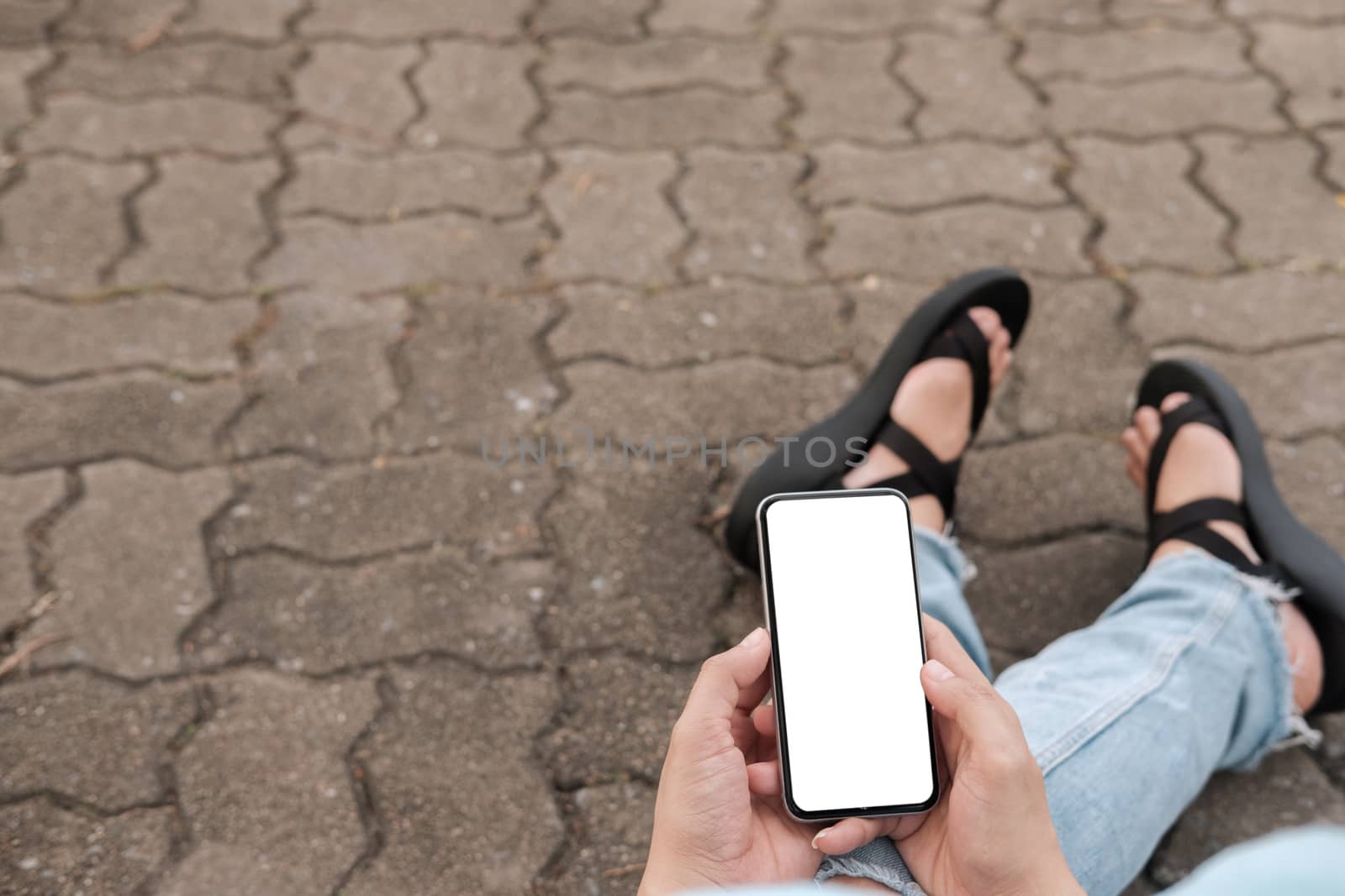 Hand's young hipster woman using smart phone on brick road.