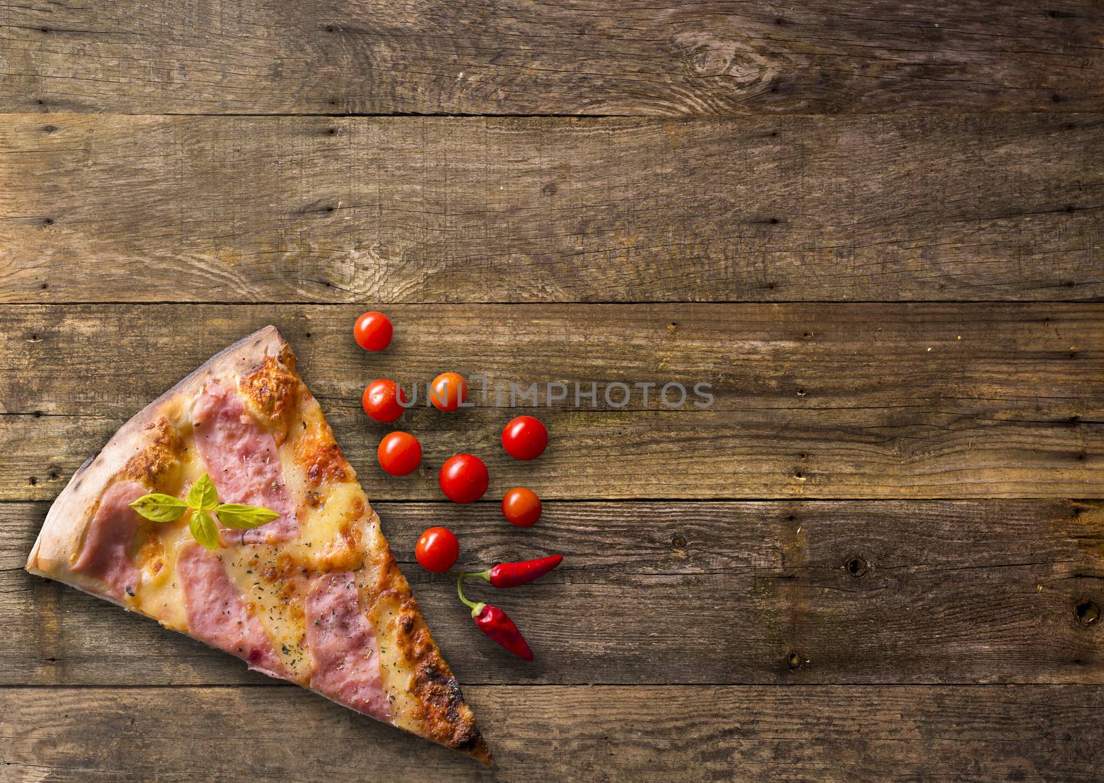 Italian food - pizza on wooden table. Cherry tomato and hot peppers around