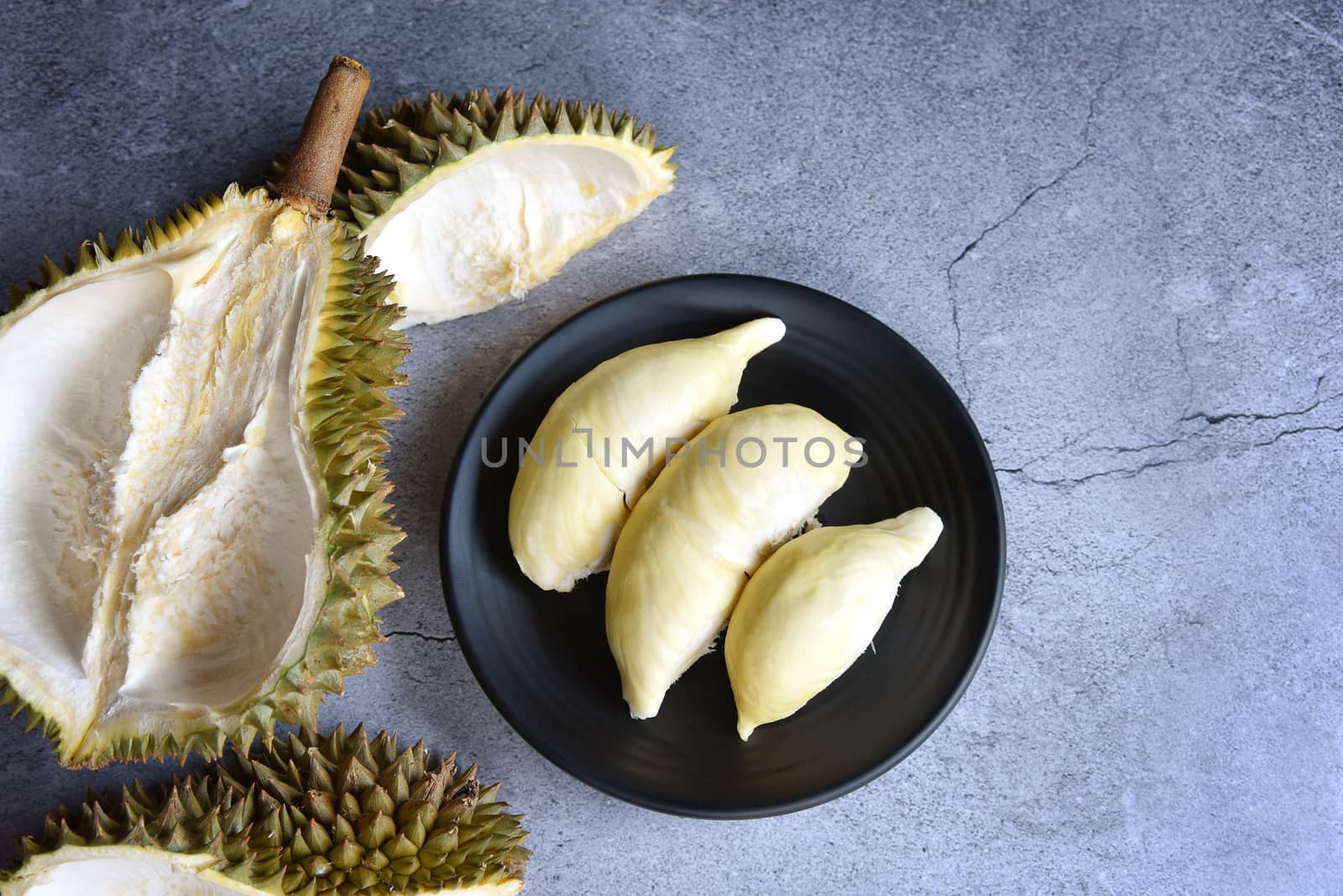 Top view Durian riped. King of Fruits. Durian is a popular tropical fruit in Thailand. Betel of durian on black dish with durian peel on Dark color background. Seasonal fruit concept. Selected focus.