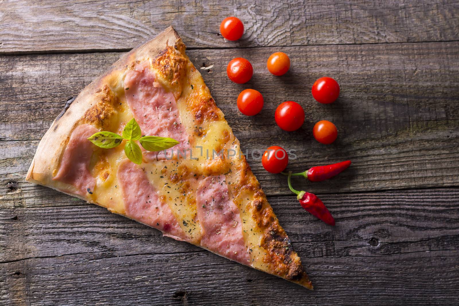 Pizza cut on wooden table, cherry tomato and hot peppers by adamr
