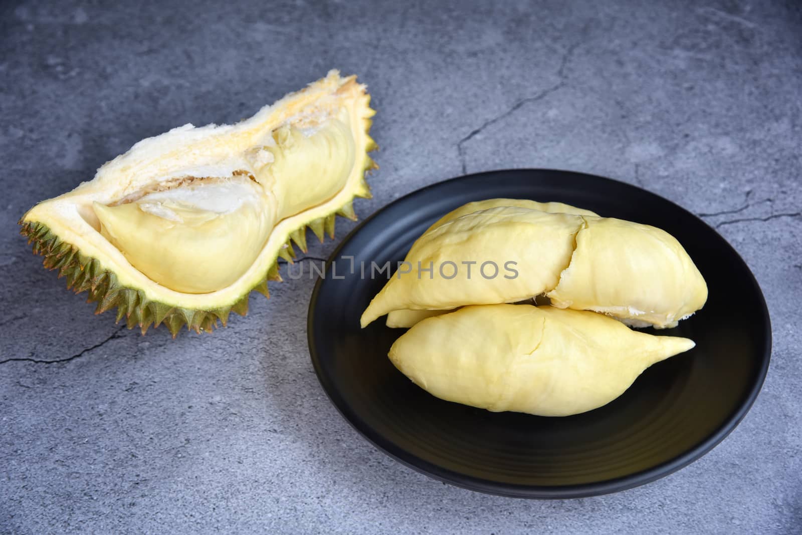 Durian riped. King of Fruits. Durian is a popular tropical fruit in Thailand. Betel of durian on black dish with durian peel on Dark color background. Seasonal fruit concept. Selected focus.