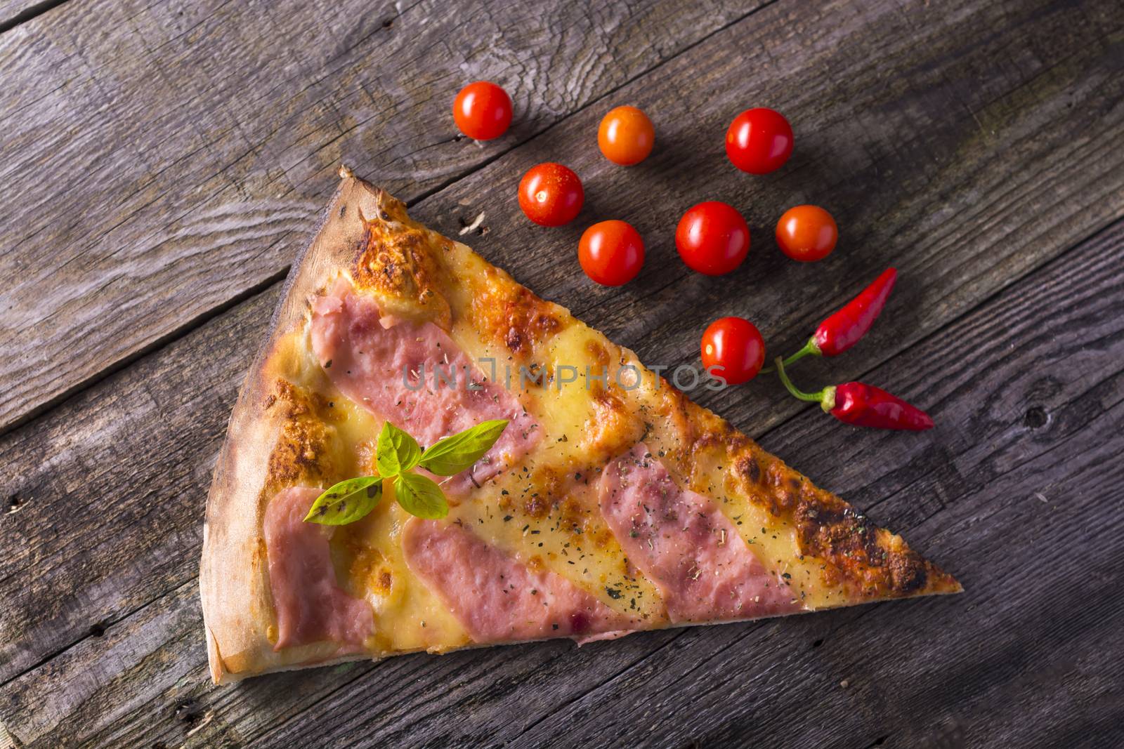 Piece of hot pizza on wooden table, cherry tomato and hot pepper by adamr