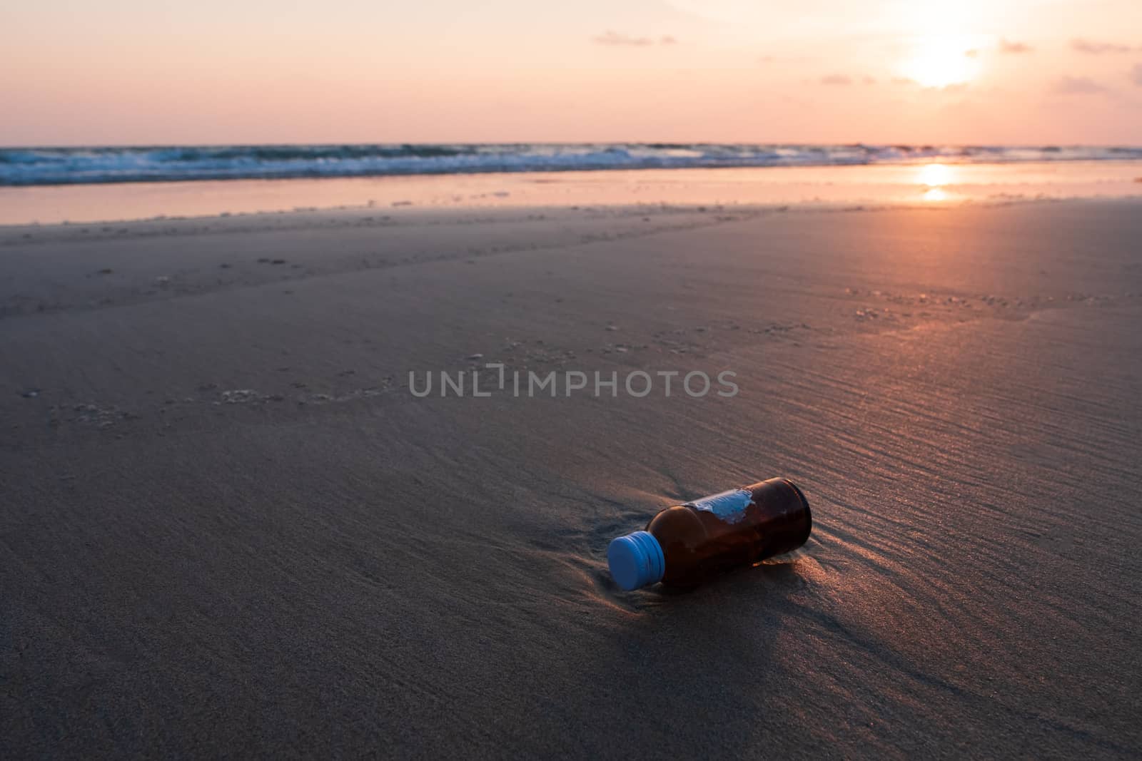 Glass bottles is dump into the sea, dirty waste on beach in summer day.