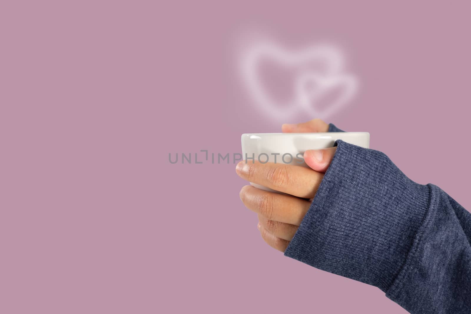 Hand holding a hot coffee cup with heart shaped smoke, love and valentine concept with copy space.