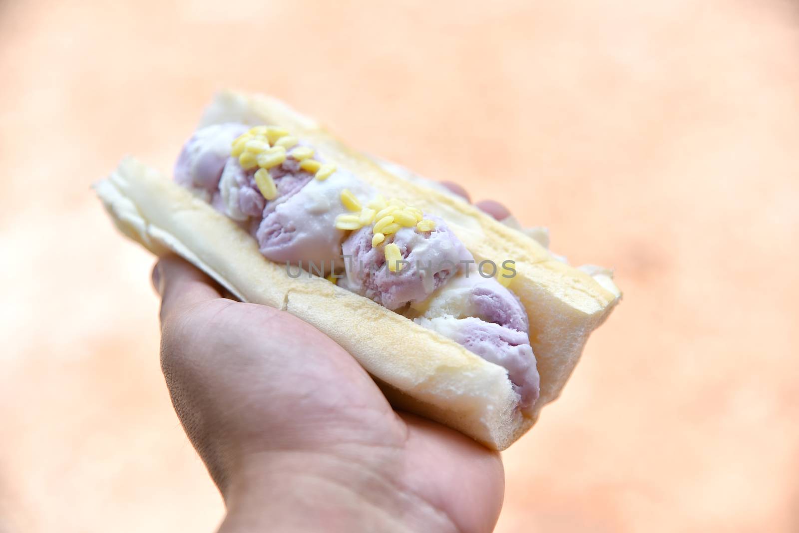 Thai style ice cream in hand, the scoops of ice cream are put in the bread. Coconut milk and Taro flavor with soybean topping. in the form bread Ice Cream Sandwich Thai style. Selected focus