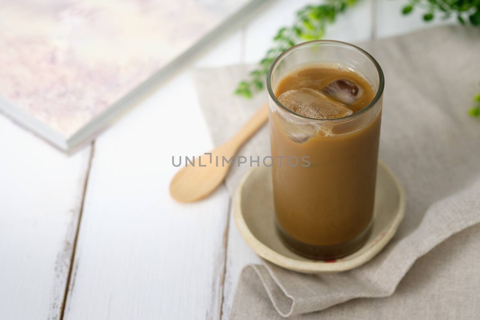 Still life - A glass with iced coffee on white wooden table.