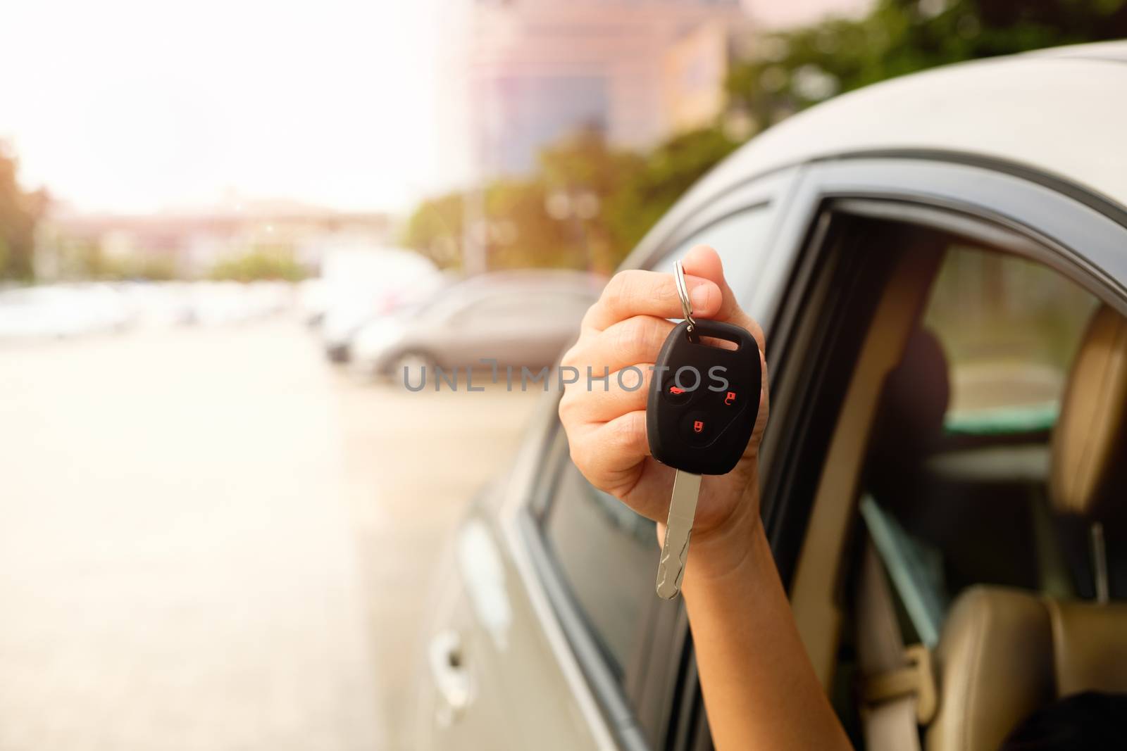 The hand of a woman holding a car key to be submitted to the driver of this car.