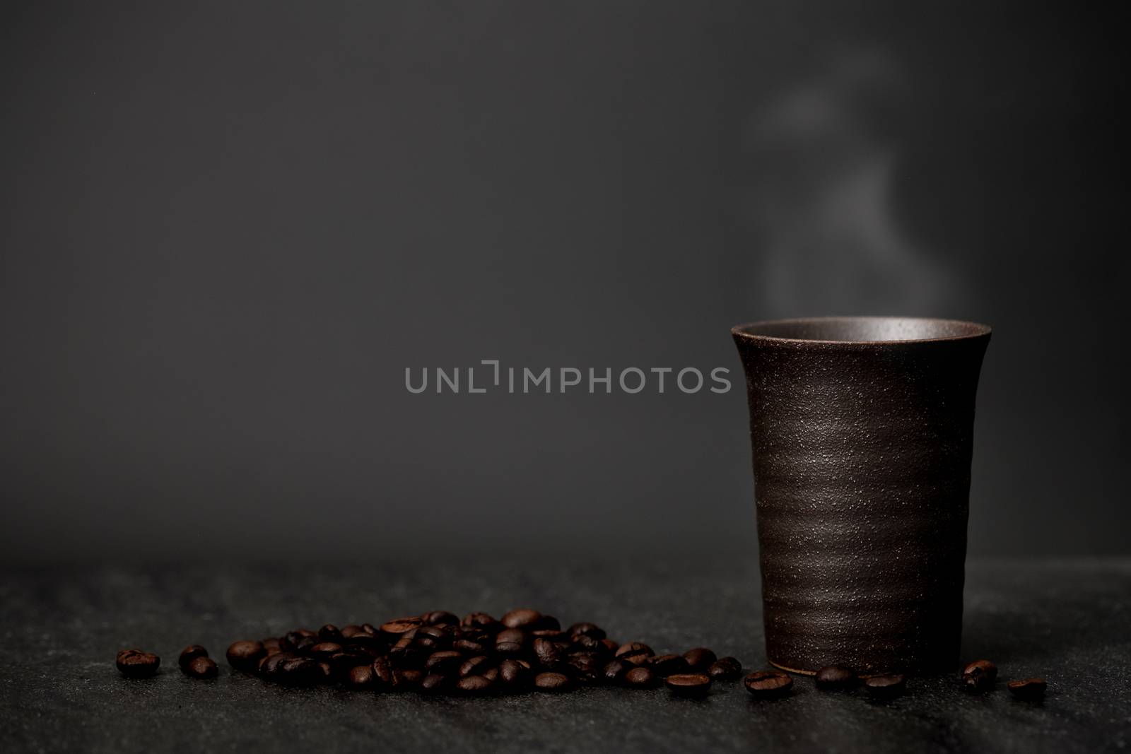 Classic still life - a cup of coffee with smoke and roasted coffee have copy space, dark light picture.