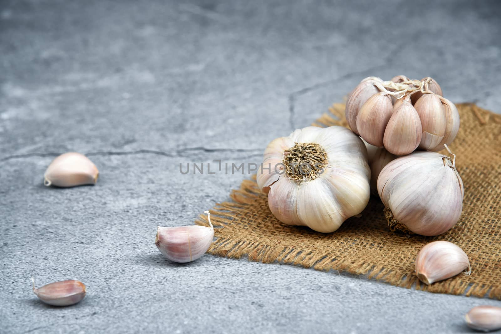 Organic Garlic. Fresh Garlic Cloves and Garlic bulb on jute on dark background with Pile of garlic or spice. Selected focus. Concept of spices for healthy cooking.