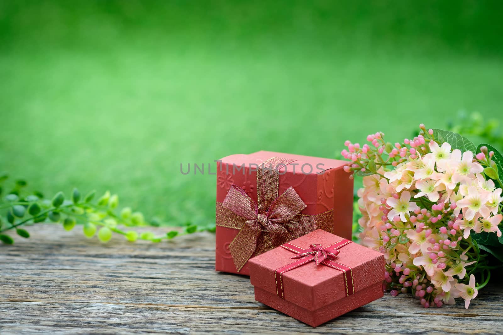 Gift box with as a present for Christmas, new year, valentine day or anniversary on decay wood in green garden background, top view, space for write.