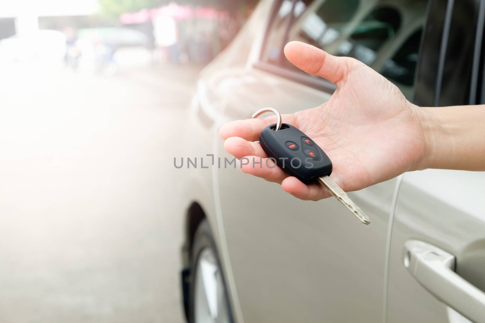The hand of a woman holding a car key to be submitted to the driver of this car.