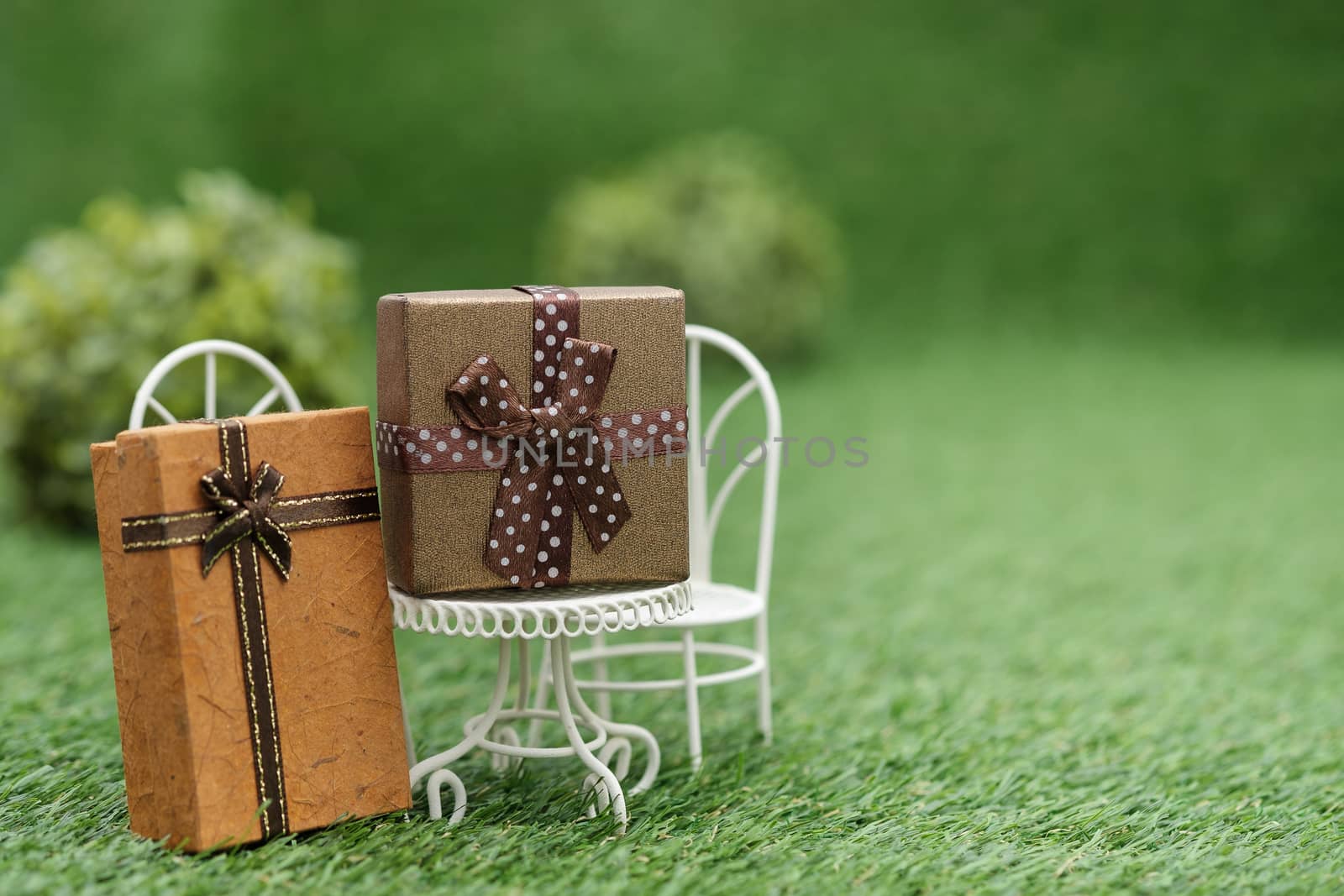 Gift box on white field chair in green garden, with copy space to write.