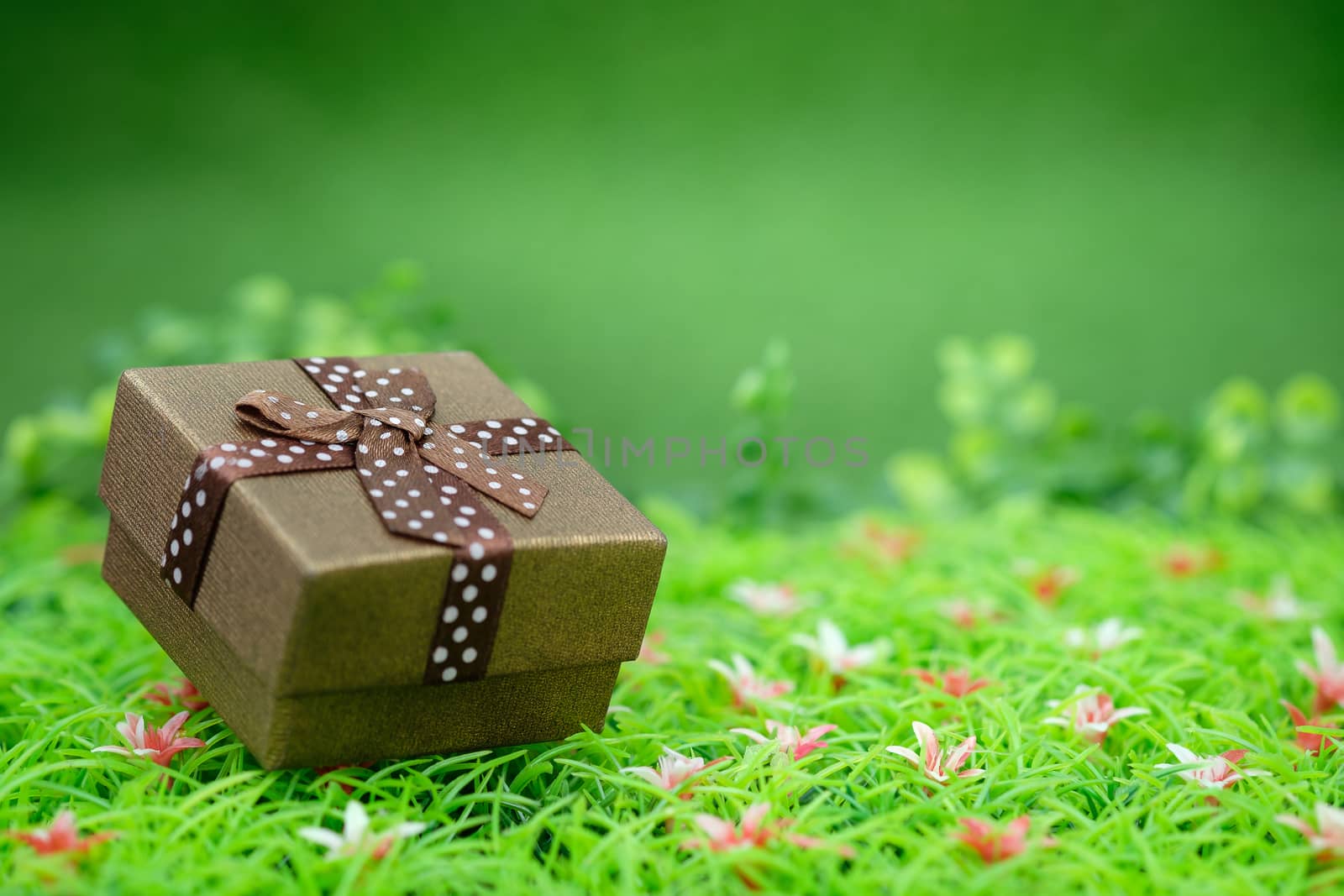 Gift box with as a present for Christmas, new year, valentine day or anniversary on green grass background, top view, space for write.