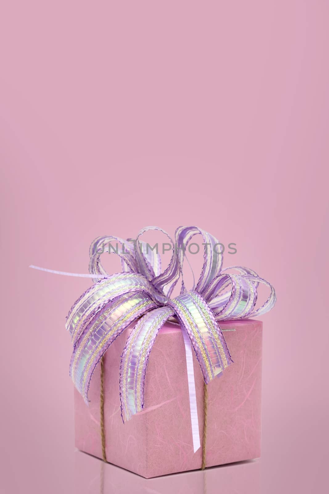 Pink gift box with ribbon with copy space on sweet background.