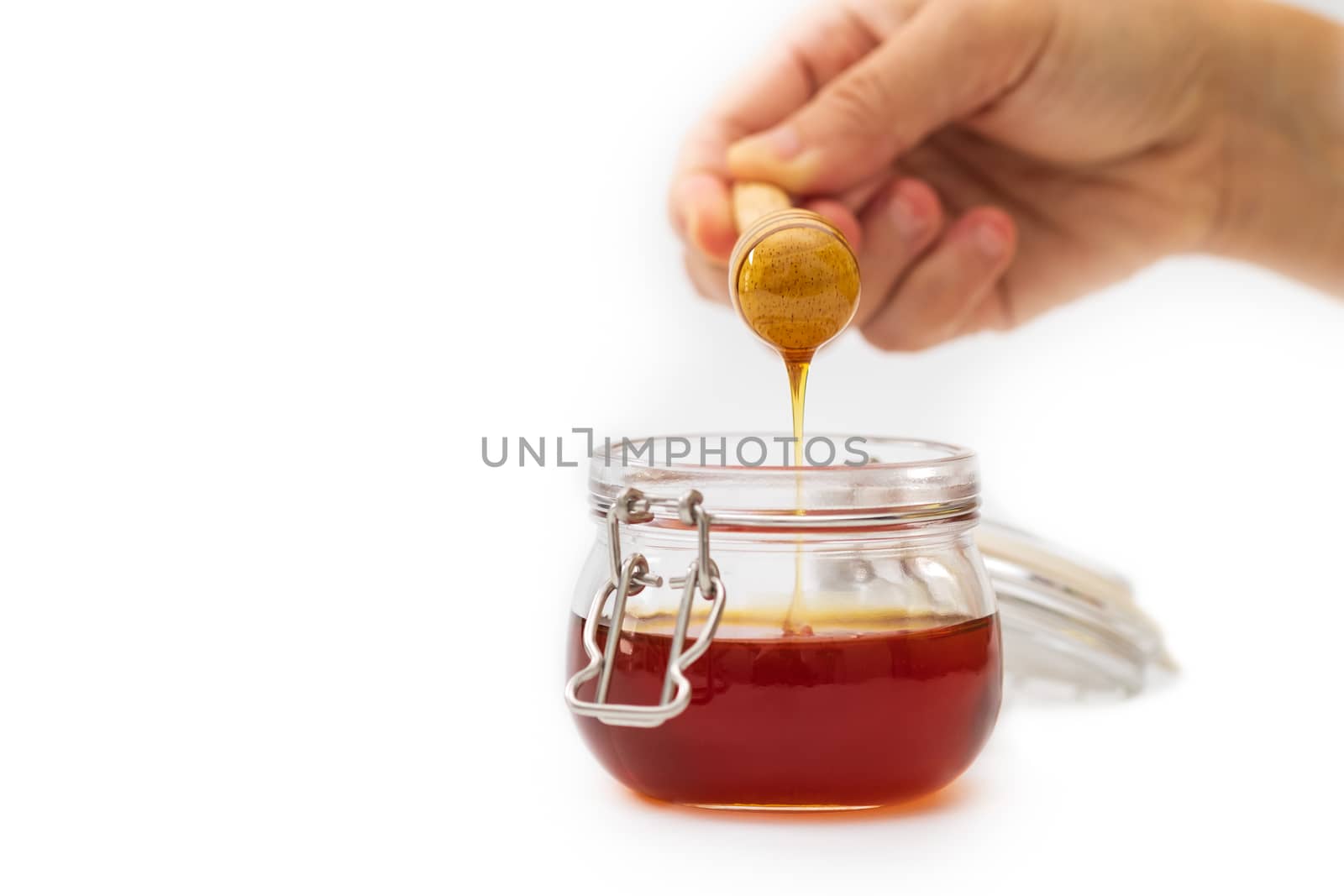 Hand holding a honey dripper on white background. Food concept.