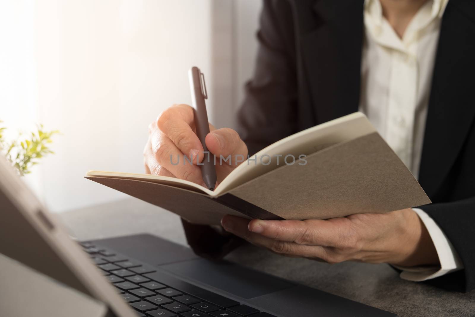 Businessmen holding a pen and writing a note in a notebook in office.
