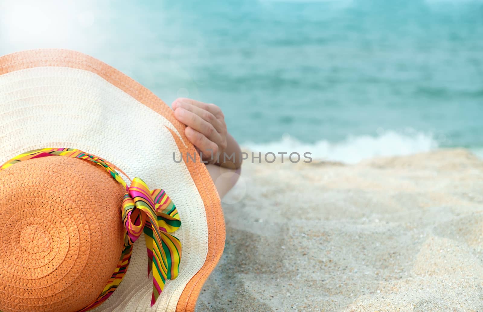 Women wearing hats are sunbathing by the sea.