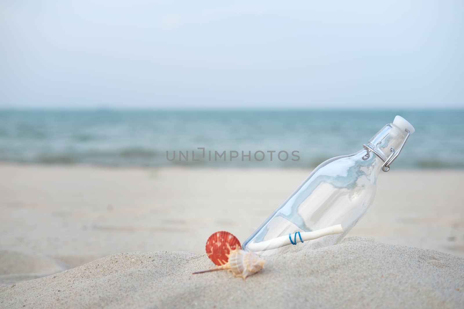 Bottle with a message on the desert beach by the sea with copy space to write.