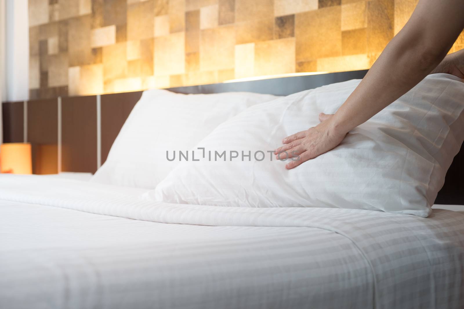Hotel room service hands set up white pillow on the bed in the h by feelartfeelant