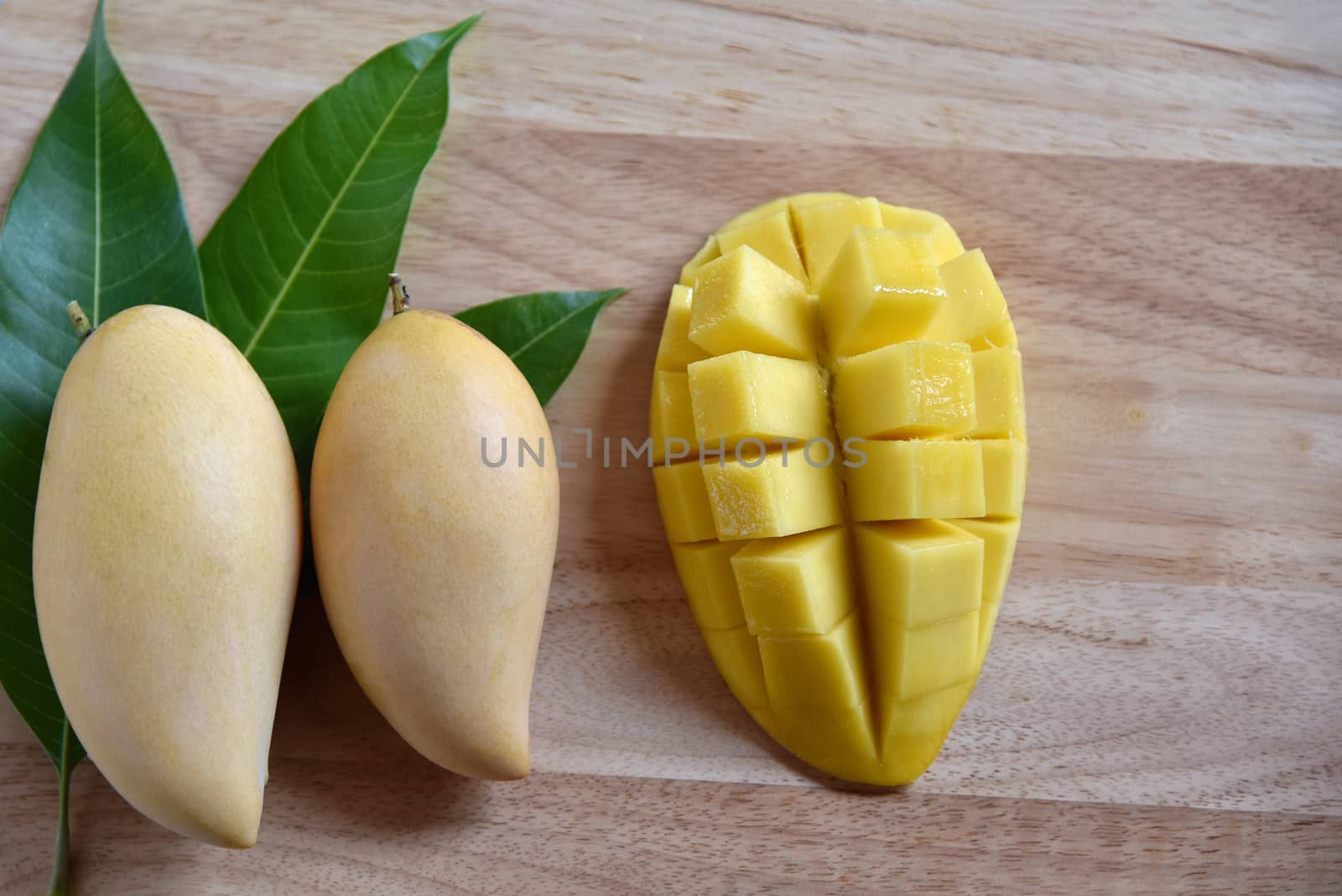 Mango. Tropical Fruits On a wooden background. Fresh beautiful mango fruit with sliced diced mango chunks. Top view. Copy space. Selected focus.
