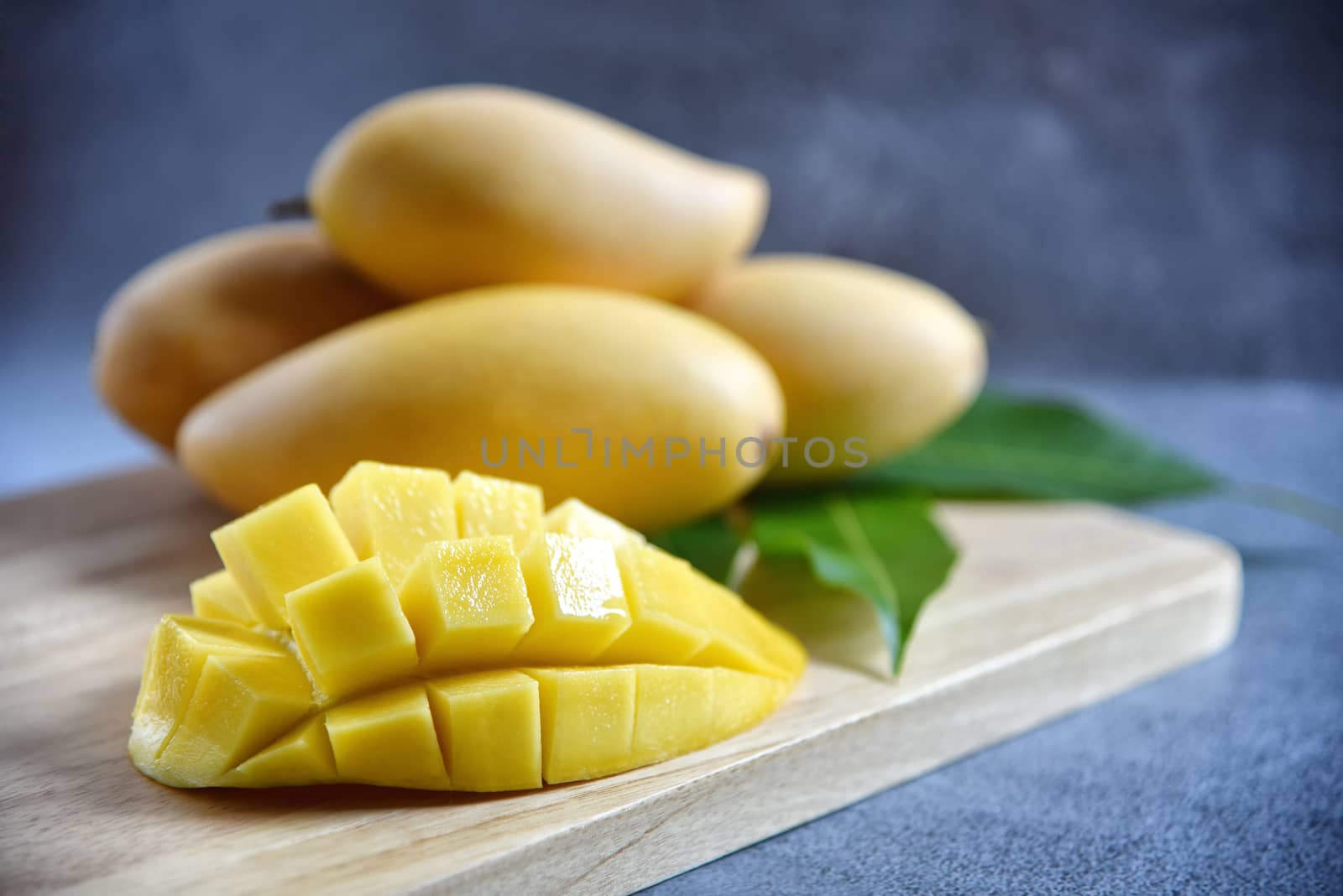 Mango slice with Fresh ripe mango and green leaves on a wooden in black  background. Tropical fruits. Selective focus. Free space for your text.