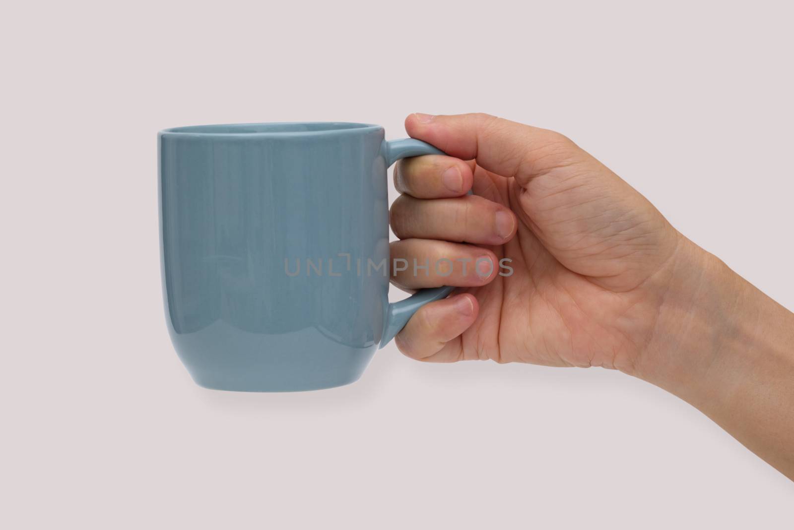 Hand holding blue ceramic mug or Coffee cup with shadow isolated on pink background.