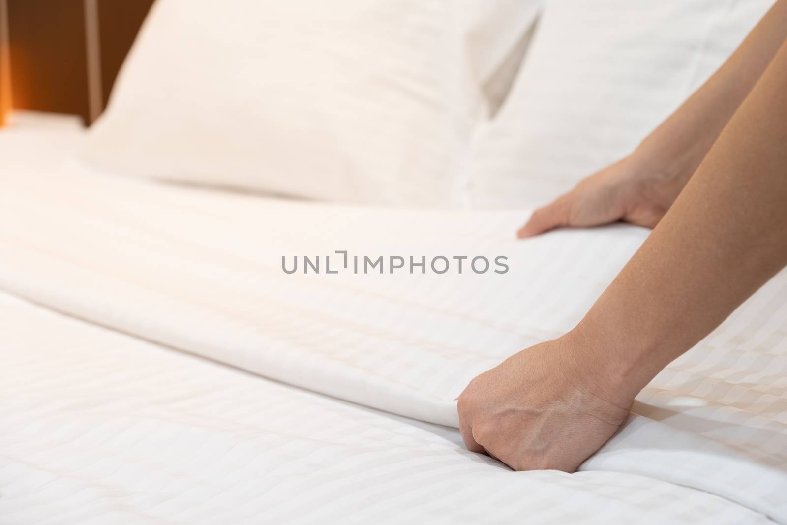 The hands of housewives who are changing sheets in hotels by feelartfeelant