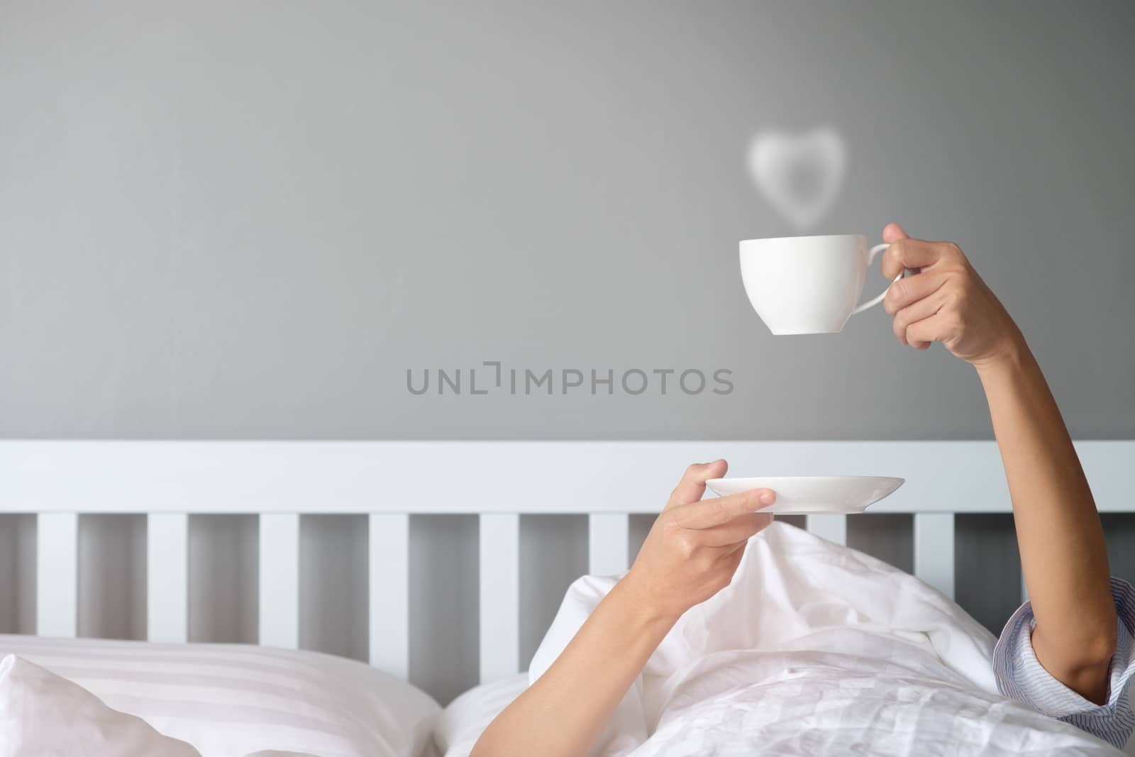 Good morning by stretching hand with a cup of coffee out of the blanket. Choose focus point, copy space.