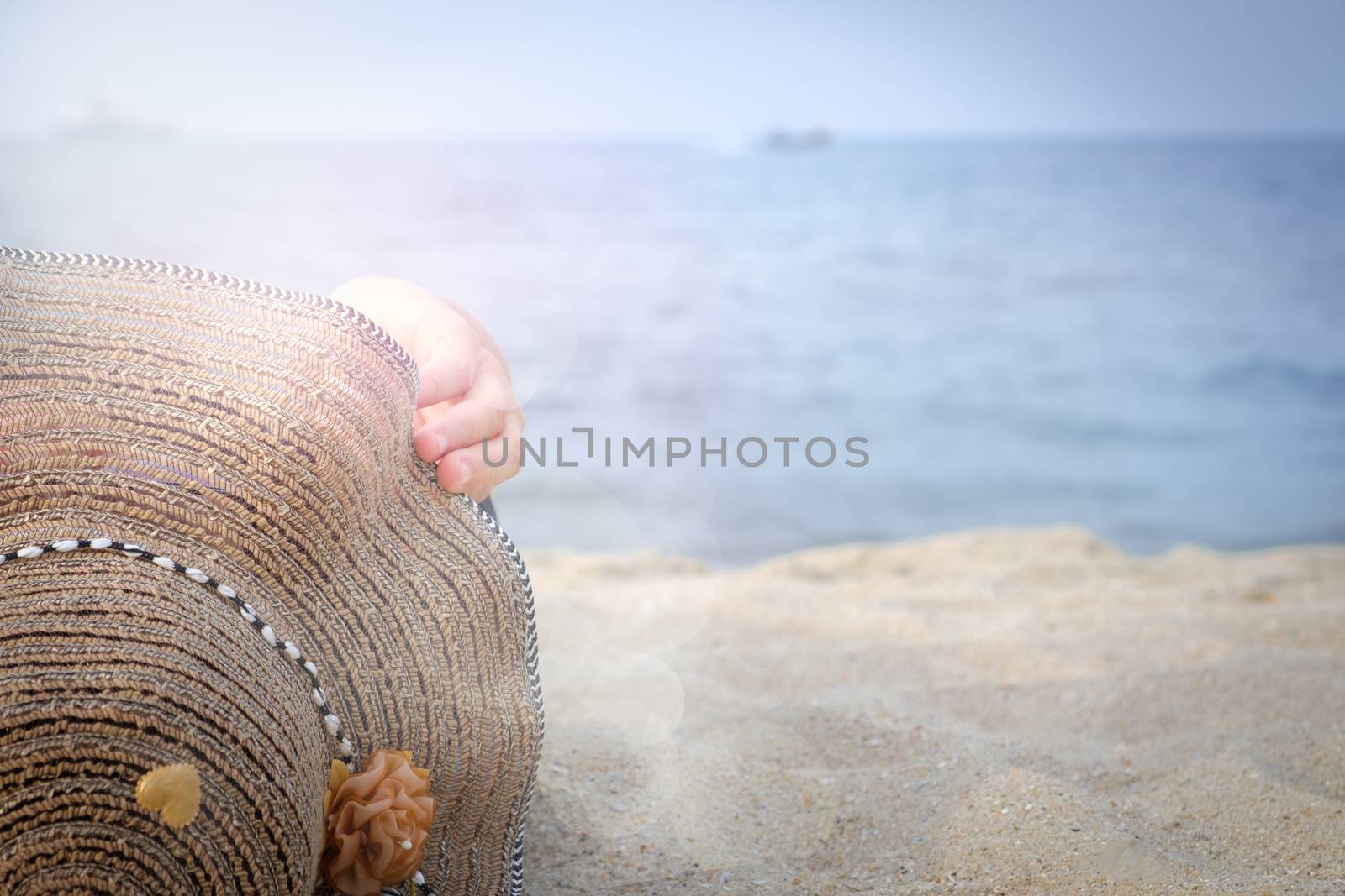 Women wearing hats are sunbathing by the sea with copy space and lens flear.
