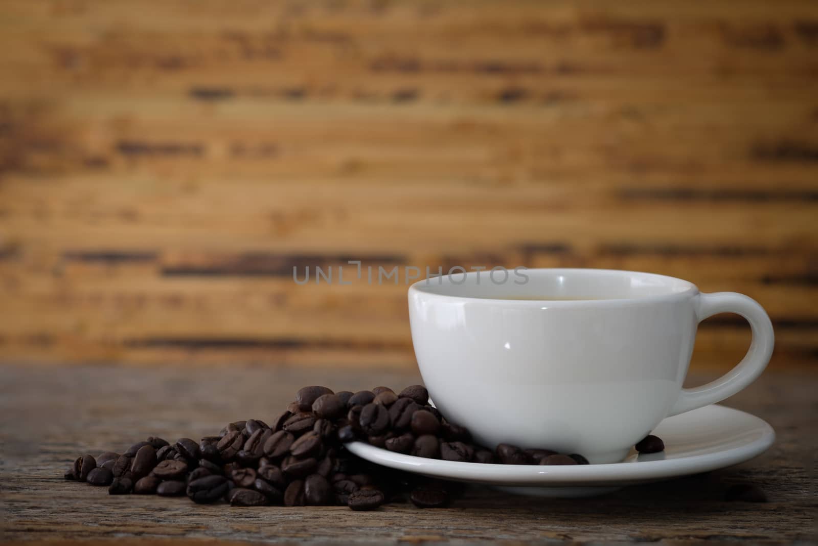 cup of coffee with roasted coffee beans 
On a wooden desk.