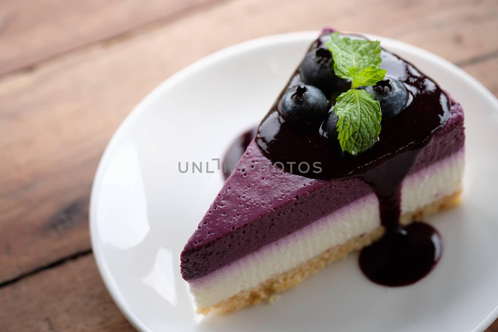 Blueberry Mousse Cake Topped with  fresh Blueberries and mint leaves.