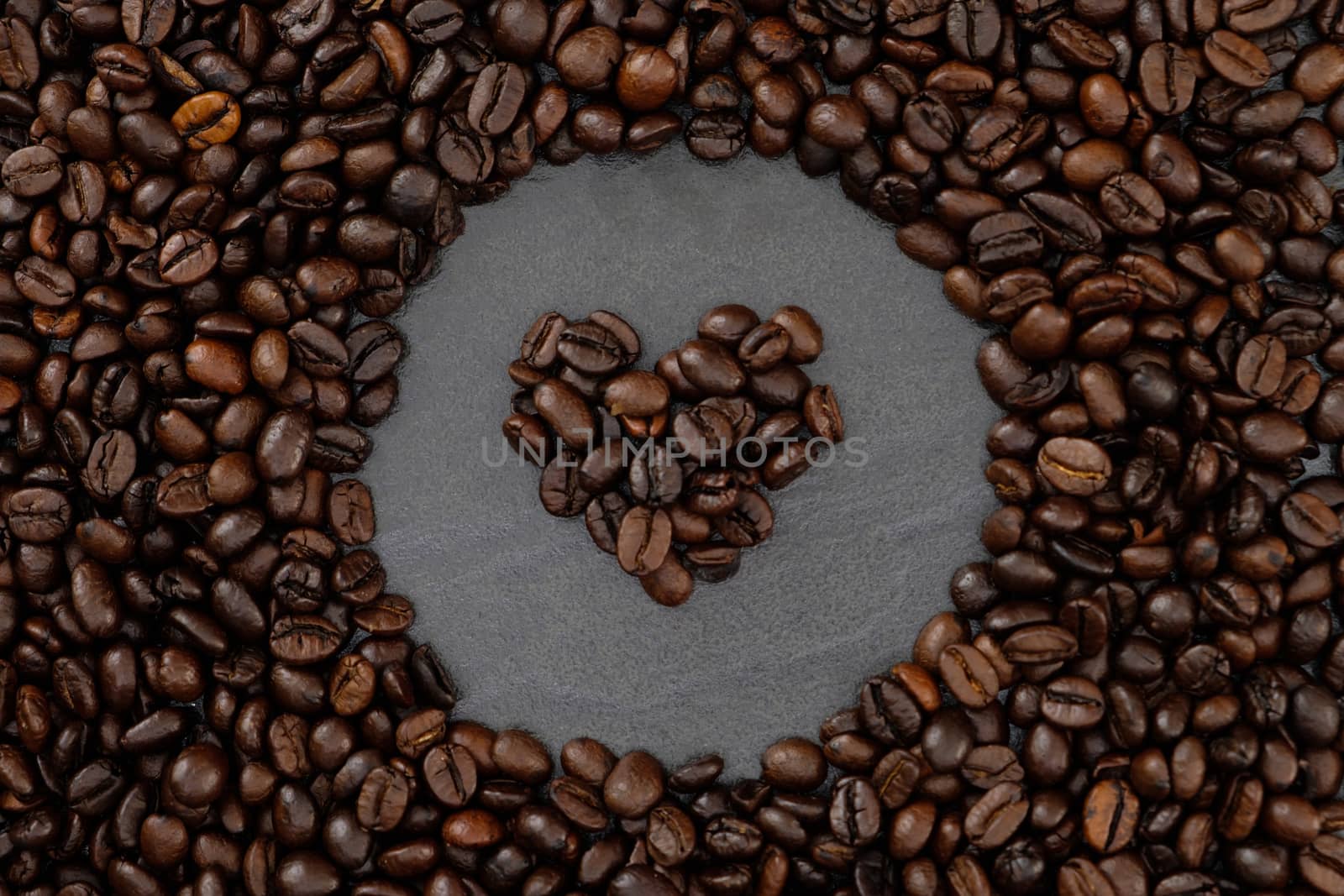 roasted coffee beans background with copy space, heart shape center.