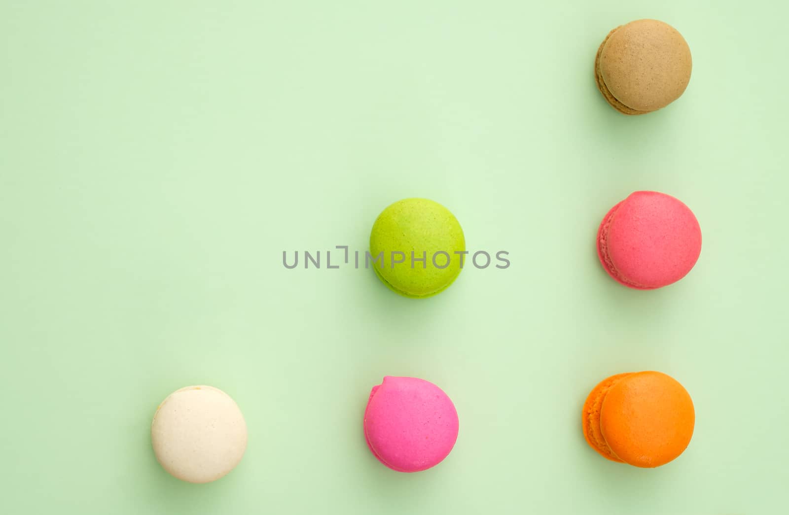 Set of different colorful macaroons on green background. Sweet and tasty for cooking and restaurant menu.