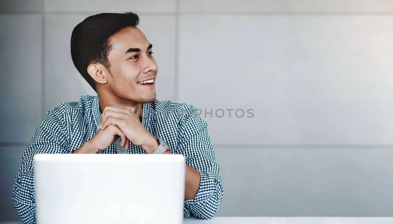 Happy Young Businessman Working on Computer Laptop in Office. Smiling and looking away