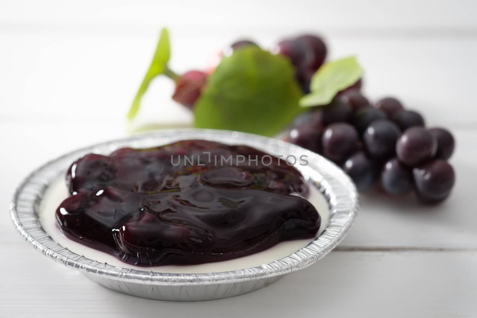Blueberry pie and purple grape placed on a white wooden floor, AF point selection.
