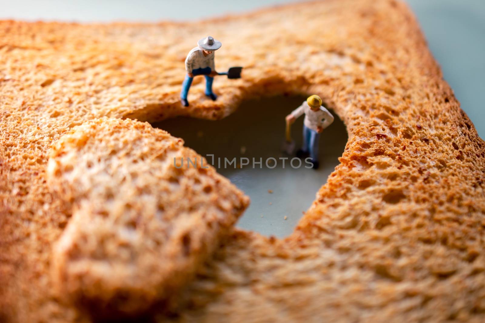 Love Concept. Sad Relationship. Group of Worker Miniature Fixing a Burned Sliced Toasted Bread with a shape of Heart