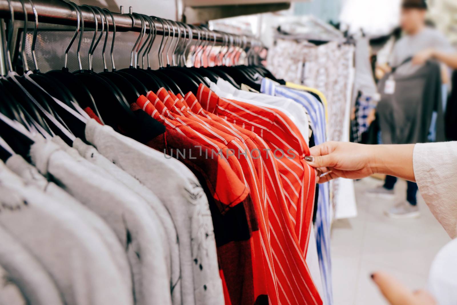 Fashion Concept. Woman Choosing Clothes on Rack in Boutique Store at Shopping Center 