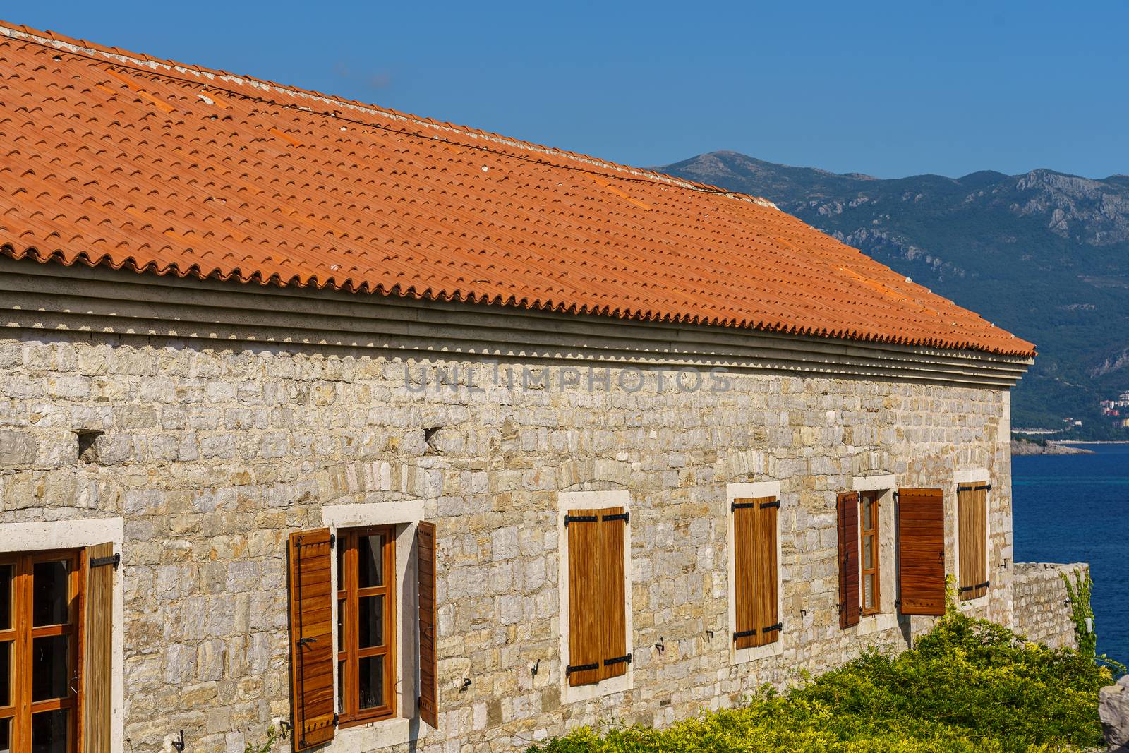 Architecture of the Balkan countries. The building is made of stone with a tiled roof and wooden shutters on the windows.