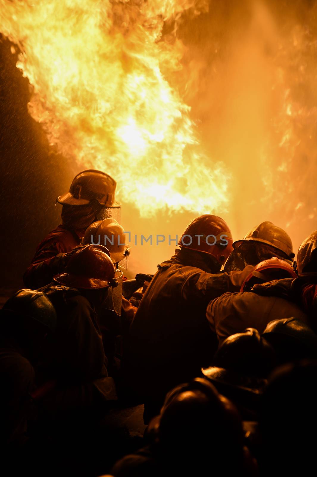 firefighters with fire hose fight with fire at night