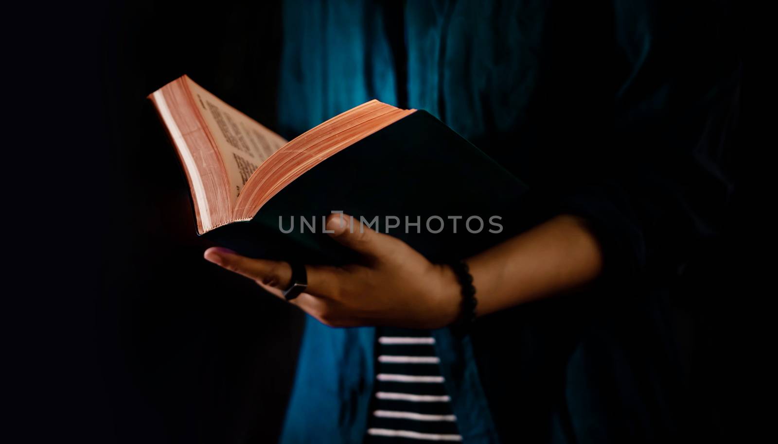 Reading Concept. Person Holding Opened Bible Book on Hand. Dark  by Black-Salmon
